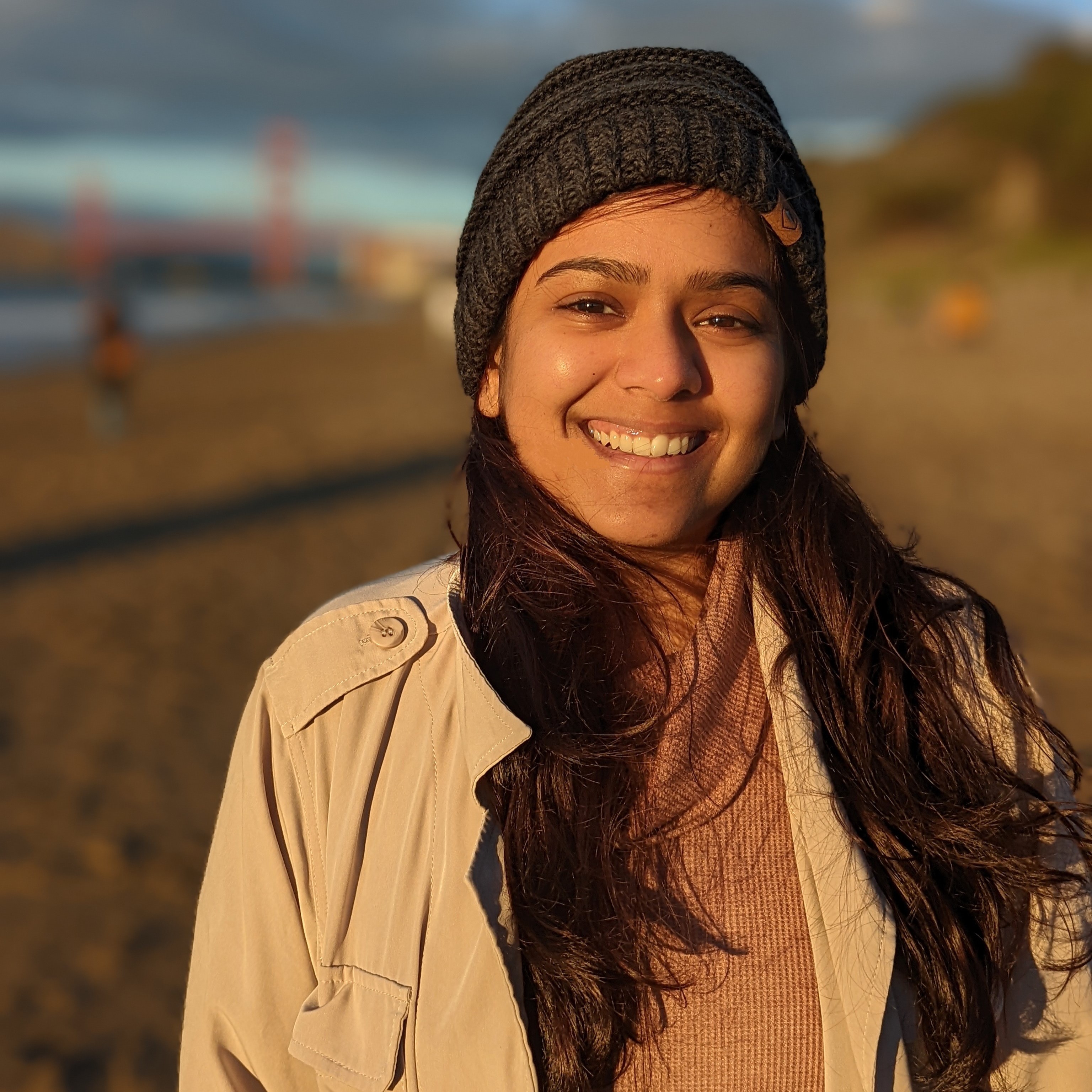 Headshot of Yeshashree with long brown hair, wearing a beanie and a coat, smiling
