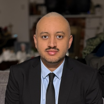 A headshot of Felipe wearing a suit jacket and tie